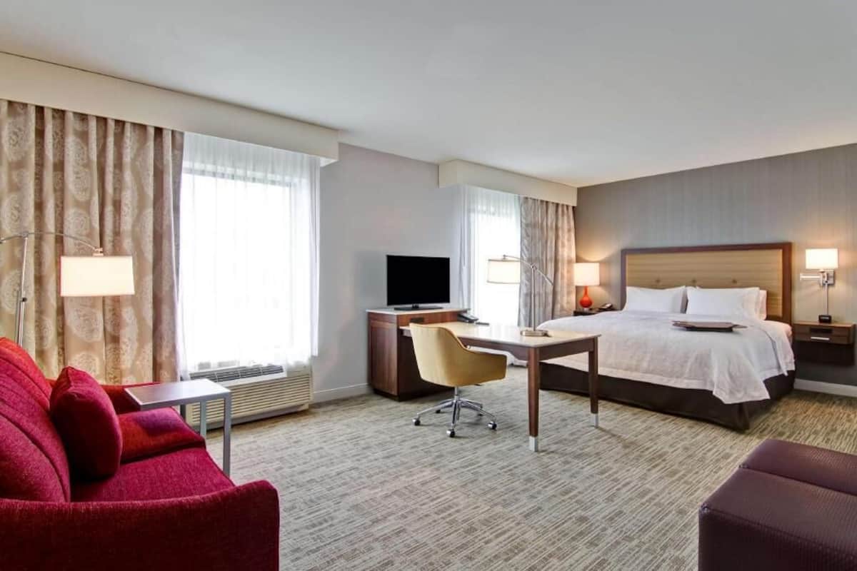 Une chambre d’hôtel équipée d’un lit, d’un bureau, d’une télévision et de deux chaises.
