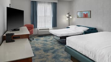 A hotel room with a TV, desk, two beds, an air conditioner, a lamp, and a cityscape painting.