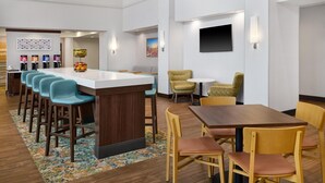 A modern hotel lobby with a bar area, seating, and a flat-screen TV. - Hampton Inn & Suites Detroit/Troy (Troy)