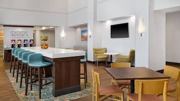 A modern hotel lobby with a bar area, seating, and a flat-screen TV.