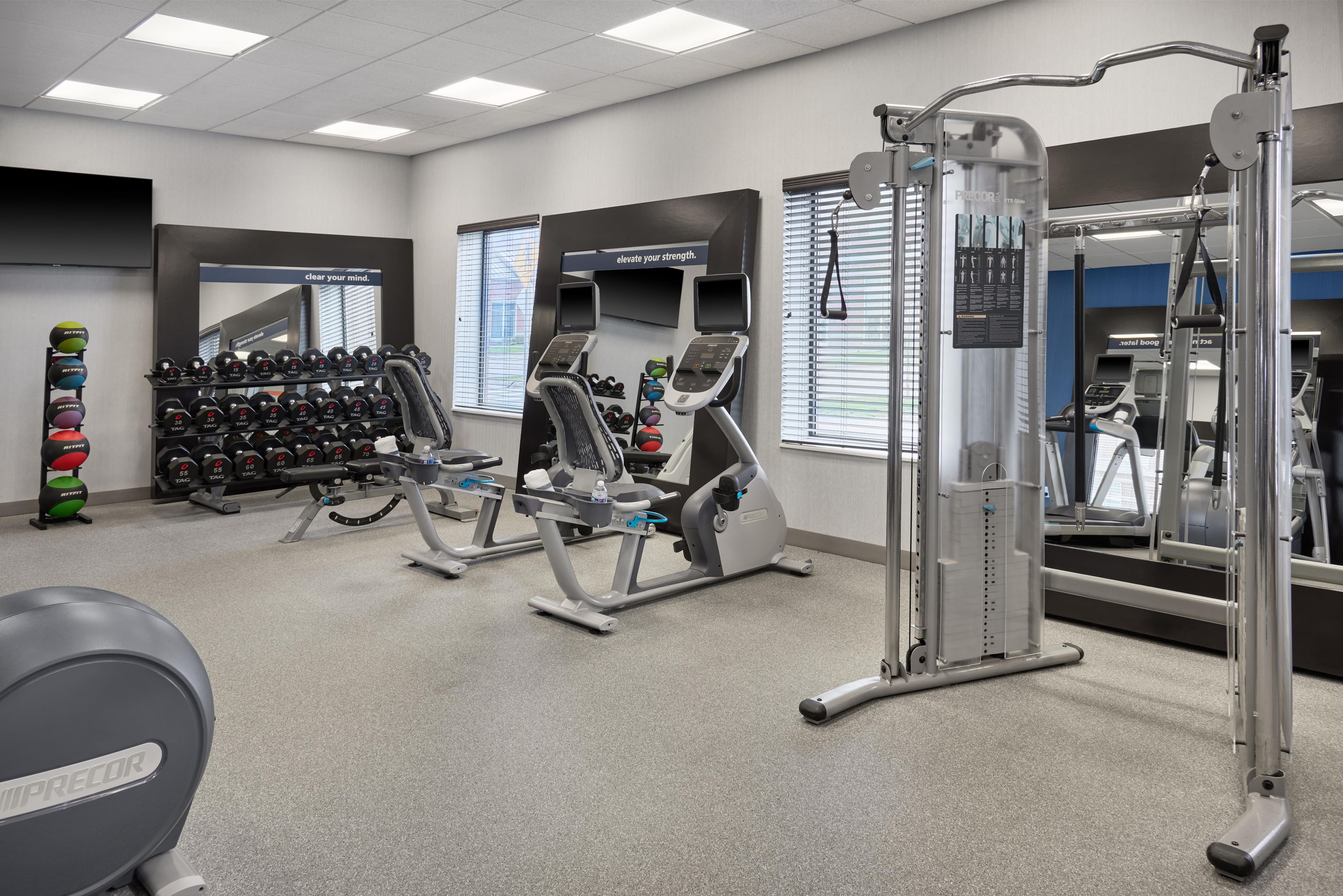 A gym with exercise equipment, weight racks, and motivational posters.