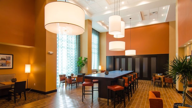 A hotel lobby with a bar area, seating arrangements, and a large window with patterned curtains. - Hampton Inn & Suites Huntsville (Huntsville)