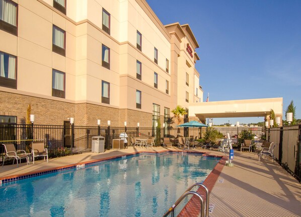 A hotel pool area with a clear blue pool, lounge chairs, and umbrellas. - Hampton Inn & Suites Huntsville (Huntsville)
