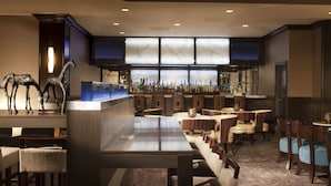 A bar area with a long counter, multiple seating options, and a decorative sculpture. - Hampton Inn & Suites Huntsville (Huntsville)