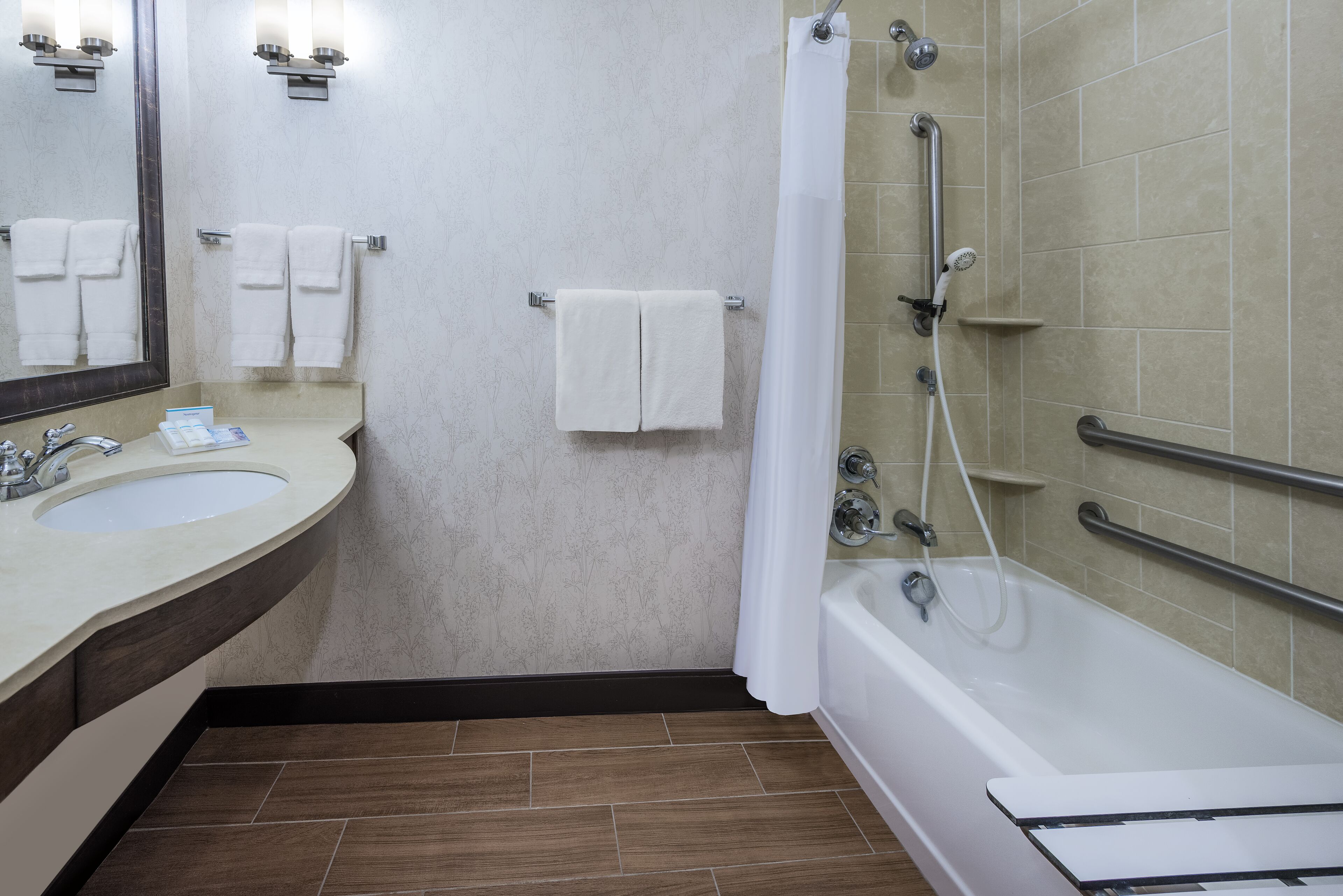 A bathroom with a sink, mirror, towel rack, shower, and bathtub.