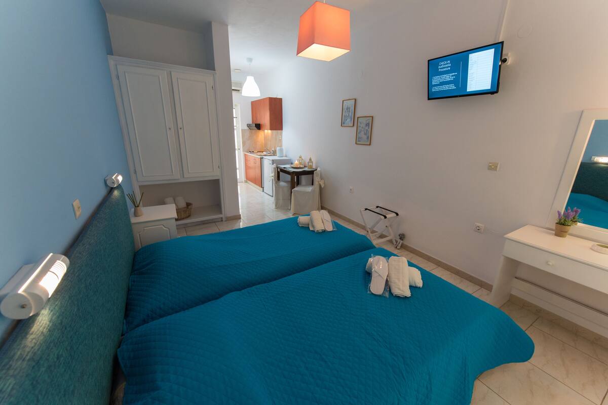 Habitación de hotel con dos camas, televisión, escritorio y baño.