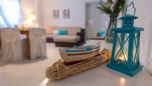 Un salón acogedor con un modelo de barco en una mesa, un farol color turquesa y un sofá al fondo.