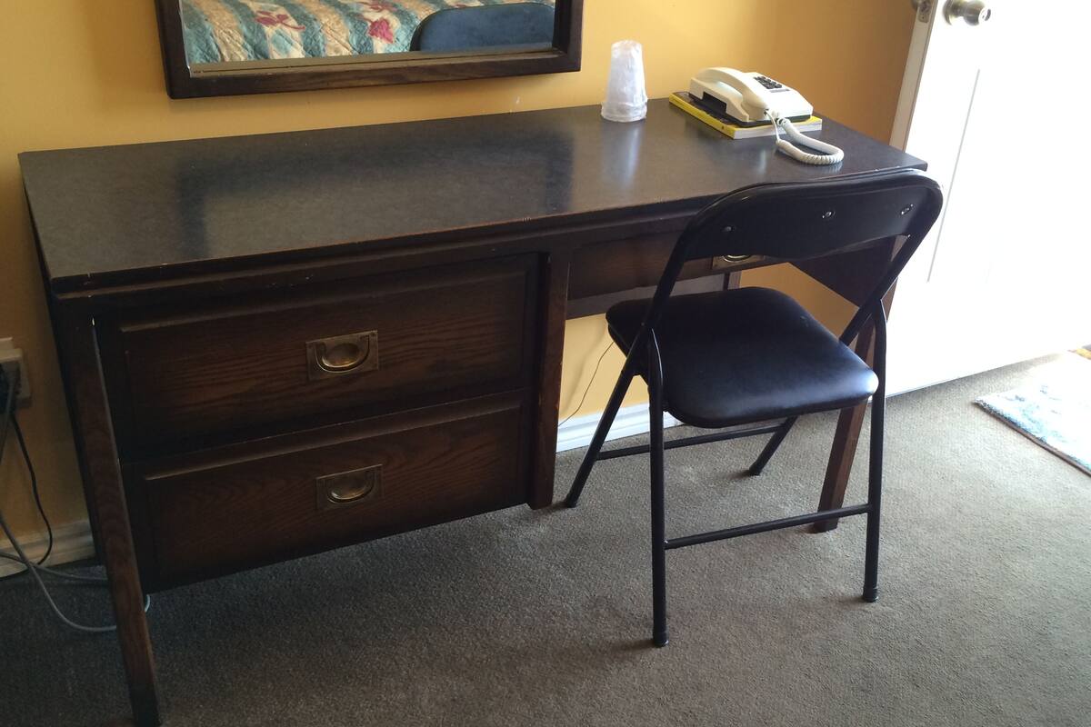 Un escritorio de madera oscura con dos cajones y una silla.