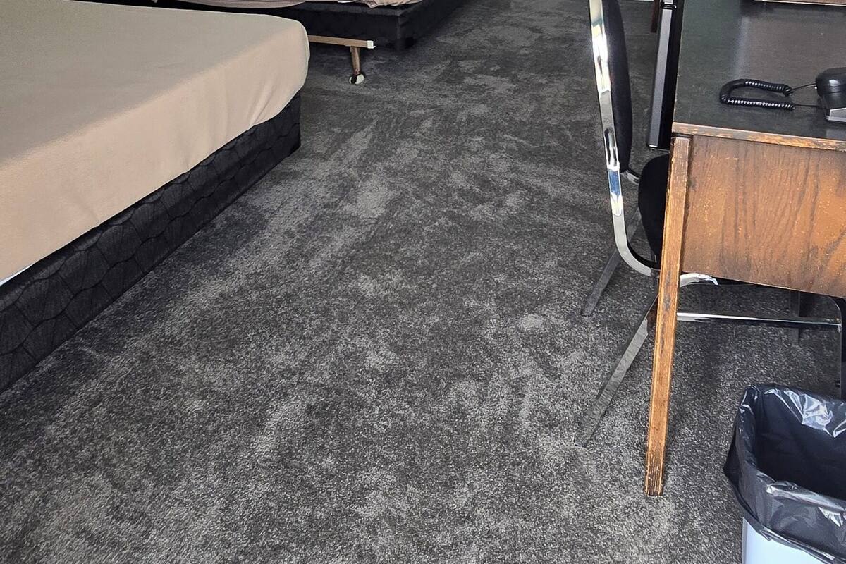 Una habitación de hotel con dos camas, un escritorio, una silla, una lámpara y una luz en el techo.