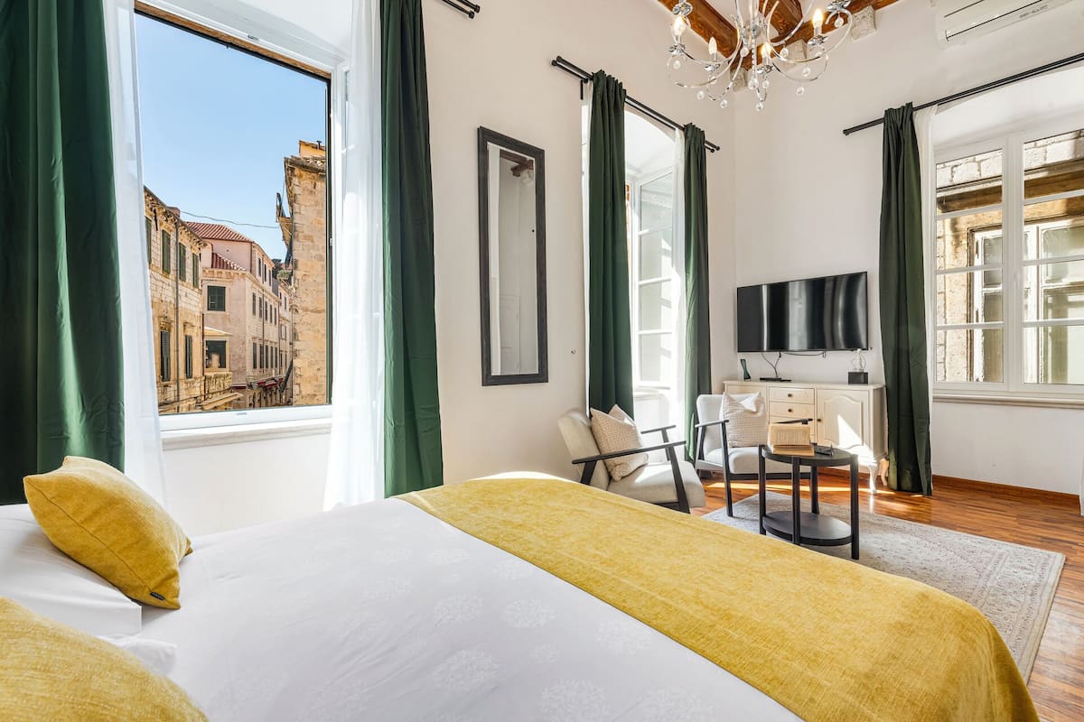 Une chambre d’hôtel équipée d’un lit, d’un bureau, d’une chaise, d’une télévision et offrant une vue sur le paysage urbain.
