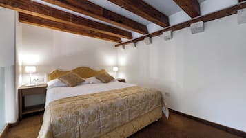 Un dormitorio con cama, lámparas de noche, techo de madera y suelo alfombrado.