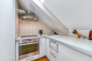 A kitchen with a built-in oven, a coffee maker, and a knife block on the counter. - Palmotta Palace (Dubrovnik)