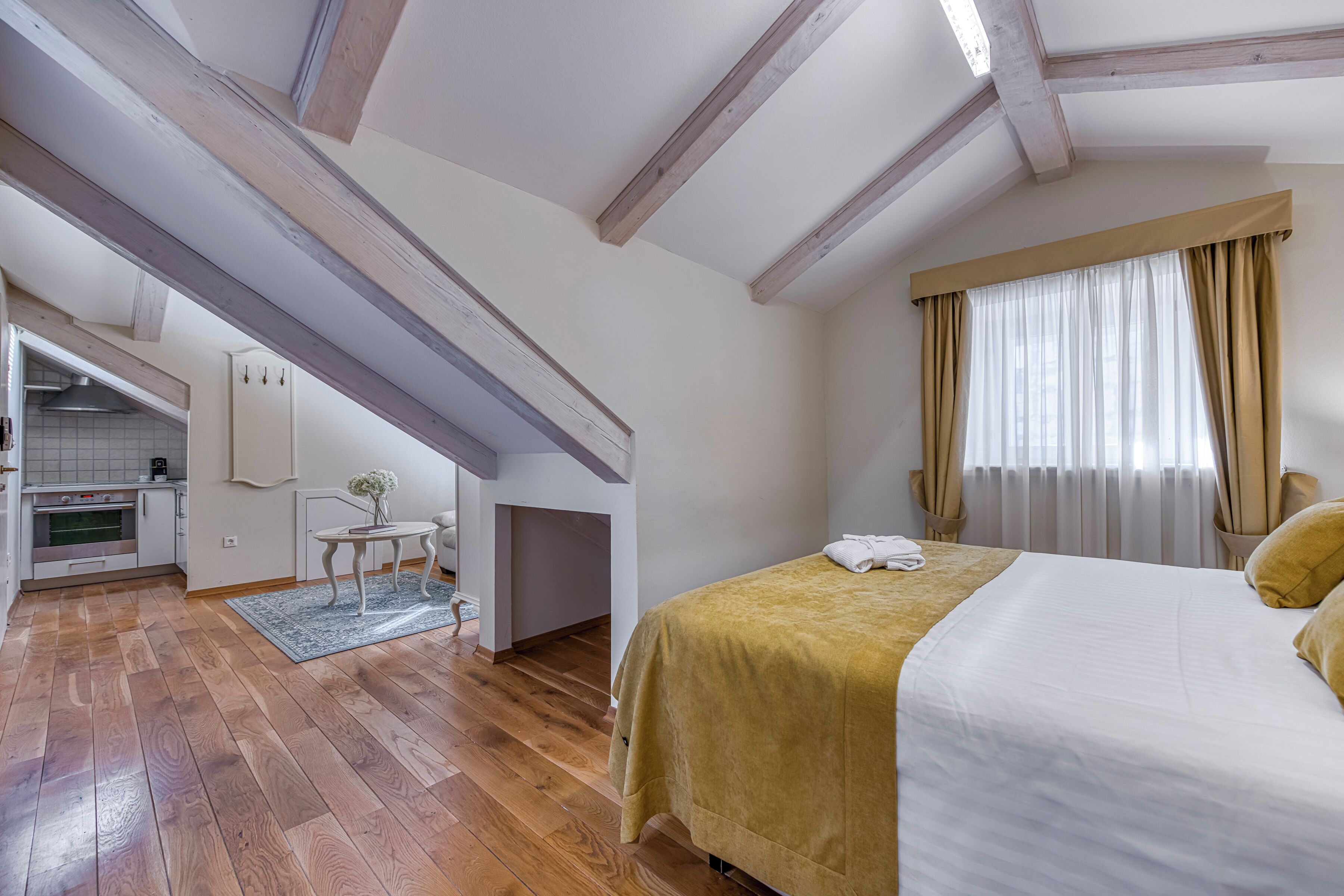 Una camera da letto con un letto, una finestra con tende, un angolo cottura e una soppalco.