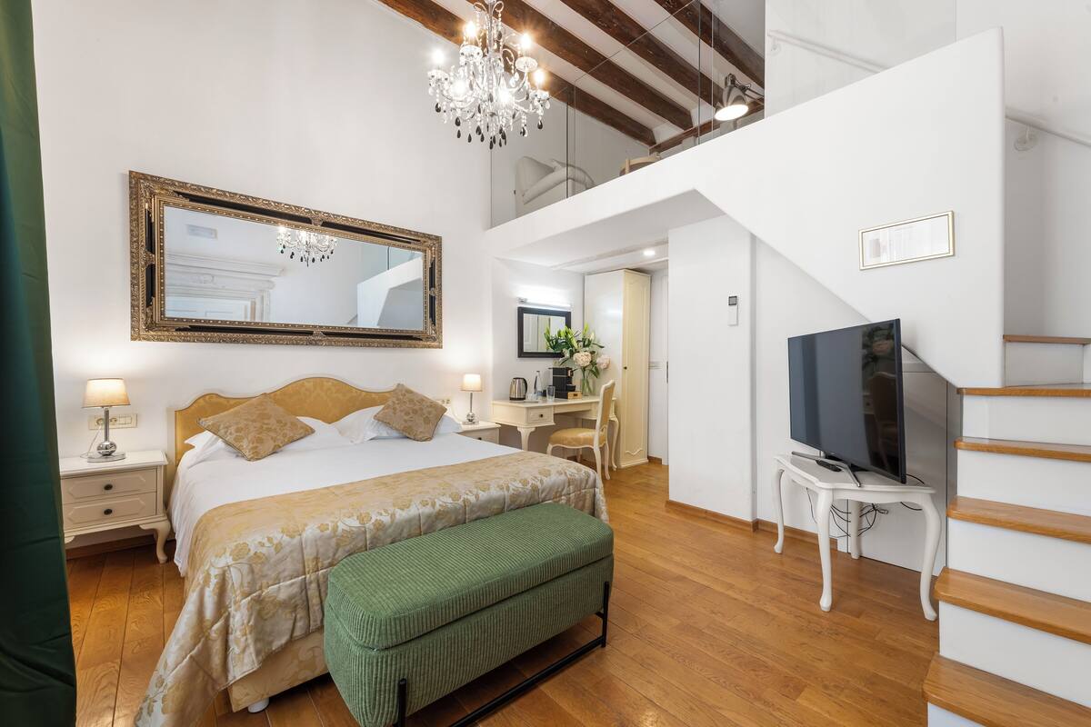 Une chambre à coucher avec un grand lit, un bureau, une télévision et un escalier.