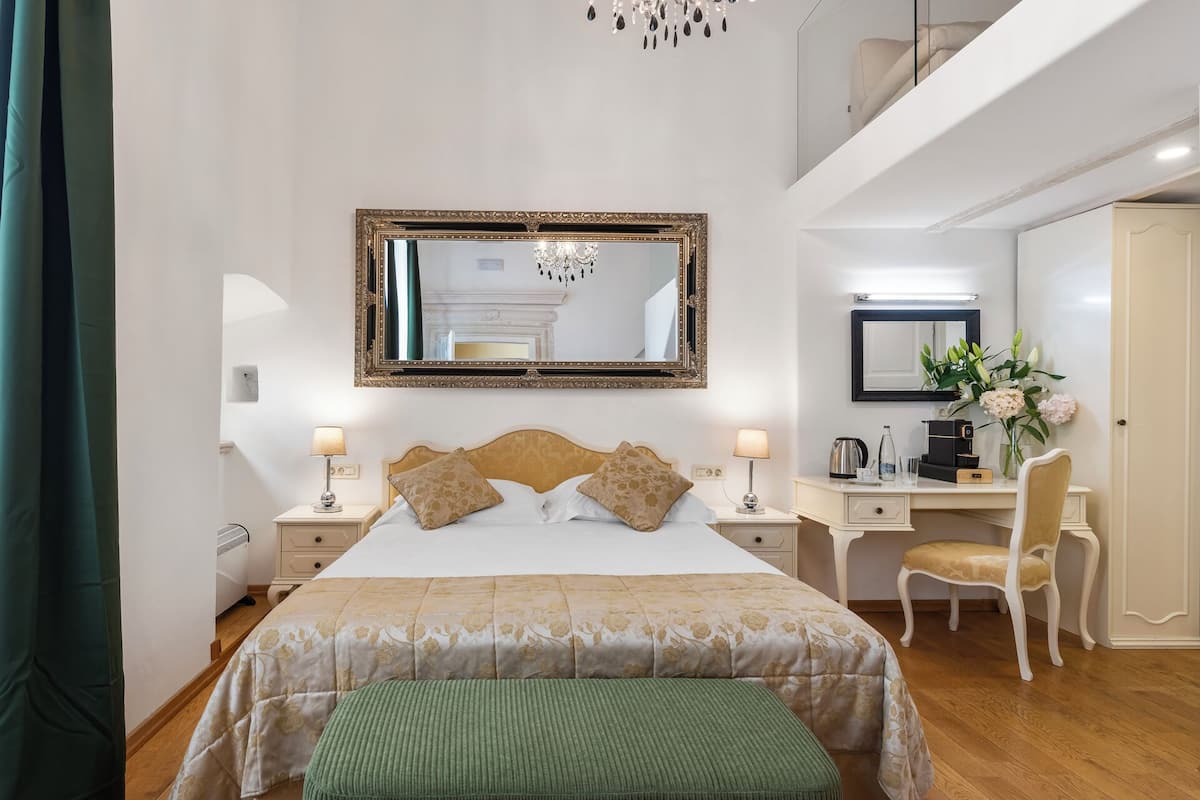 Une chambre d’hôtel avec un grand lit, un bureau, une chaise et un miroir.