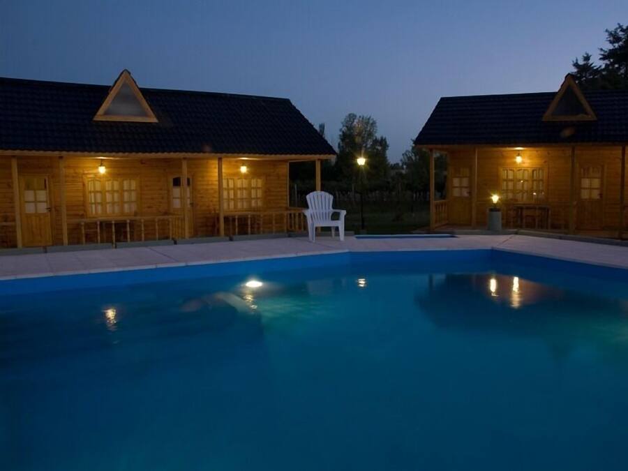 Un área de piscina con dos cabañas de madera, cada una con techo triangular y una sola ventana.