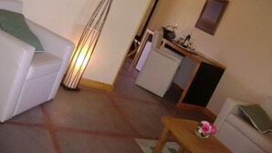 A living room with a sofa, a small table with flowers, and a kitchen area in the background. - Vistalba Lodge (Luján de Cuyo)