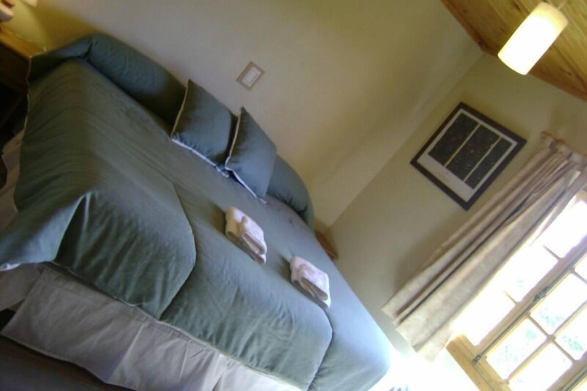A large bed with a blue and white duvet, pillows, and a folded towel on the side.