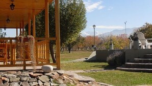 A covered outdoor seating area with stone steps leading up to a white chair, surrounded by a stone wall and a grassy area. - Vistalba Lodge (Luján de Cuyo)