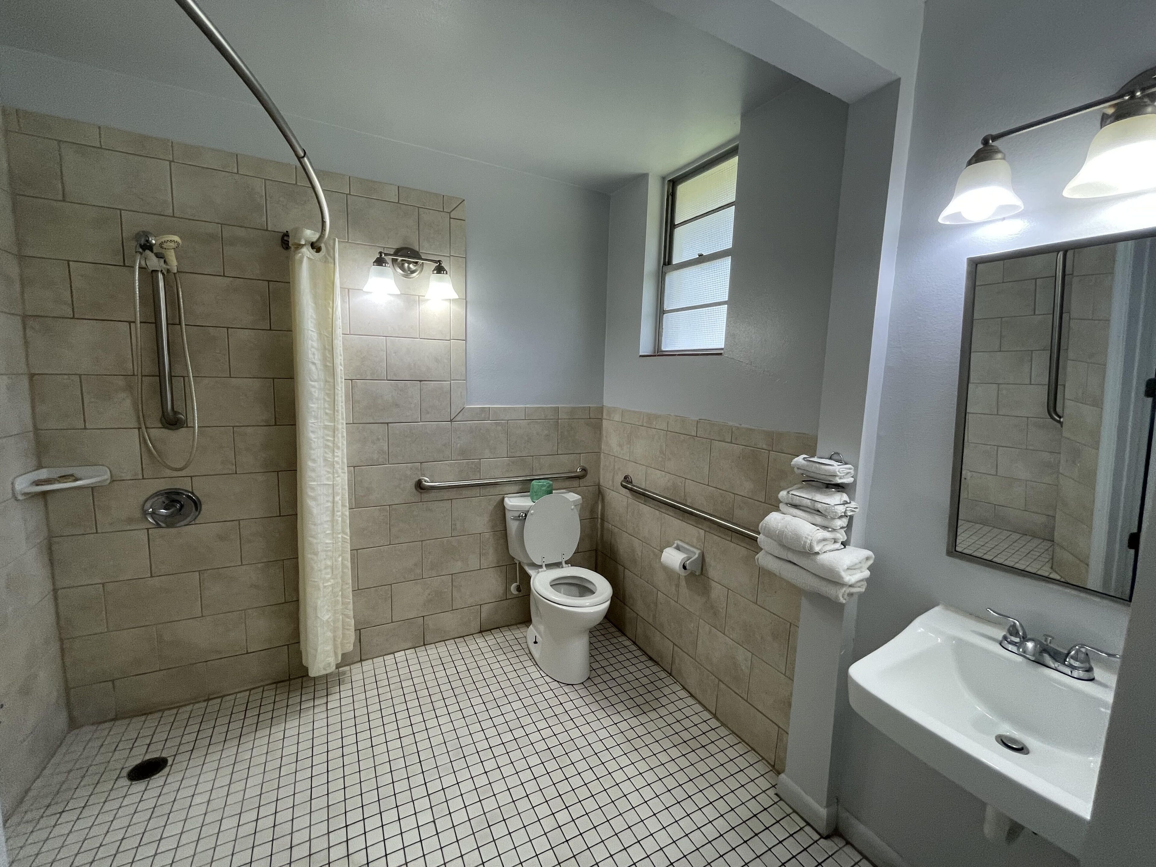 A bathroom with a shower, toilet, and sink.