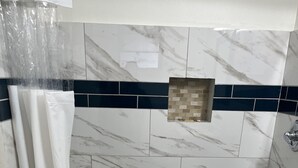 A shower area with a white curtain, a small towel, and a drain. - Castillo Inn (St. Augustine)