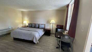 A hotel room with a bed, bedside lamps, a desk, and a window with curtains.