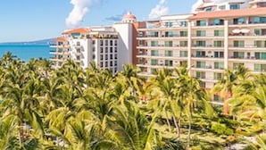 A beachfront hotel with multiple floors, balconies, and a view of the sea. - Unlimited Luxury Villas - Playa Royale Condo (Nuevo Nayarit)