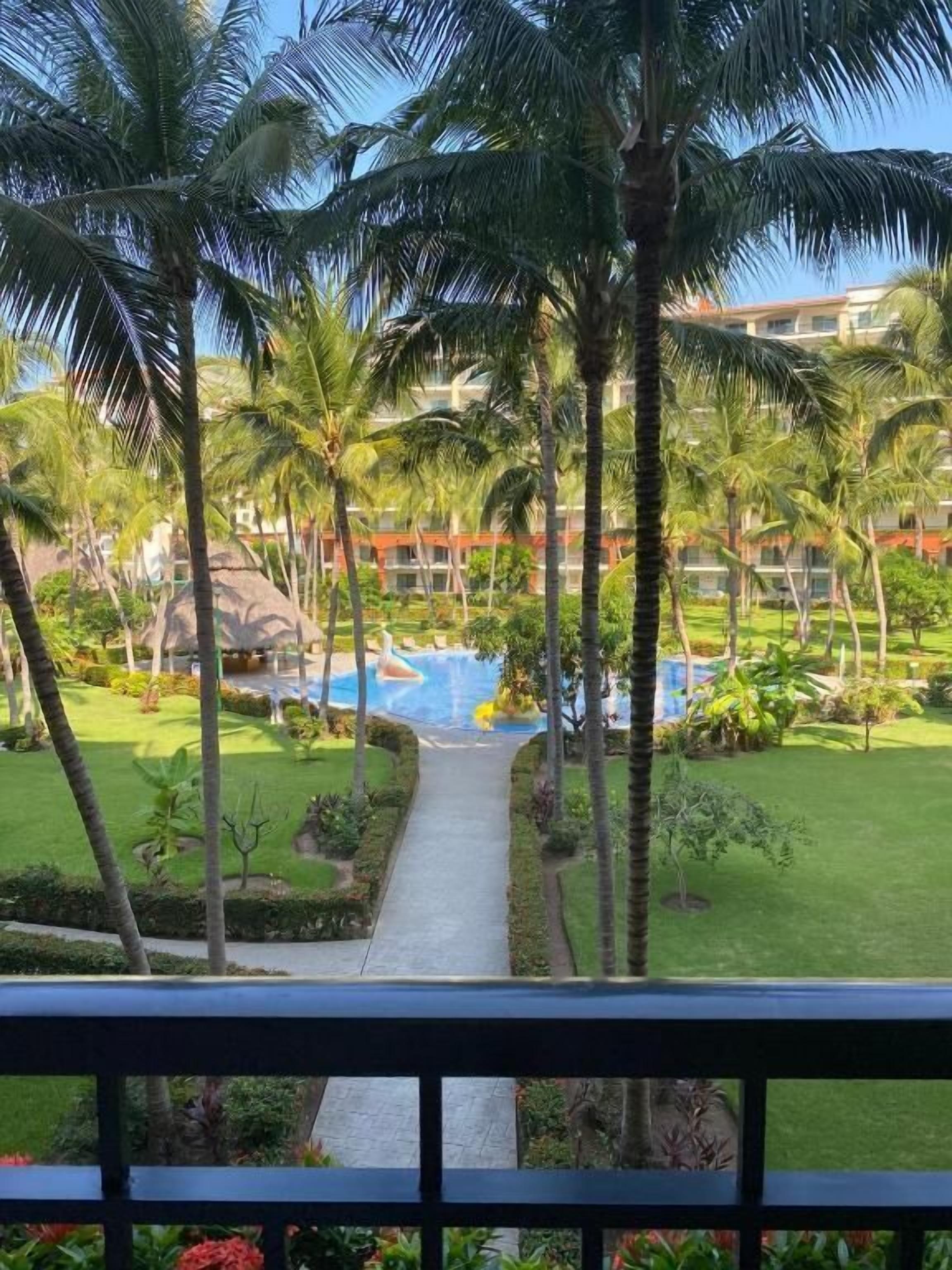 Un resort con piscina, palmeras y un camino que lleva a la piscina.