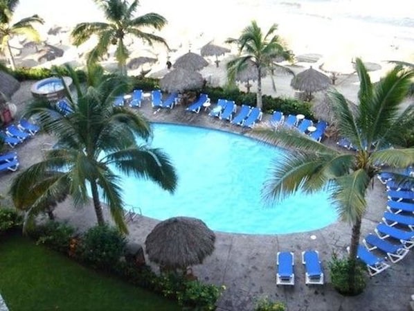 Una piscina rodeada de palmeras y sillones de descanso.