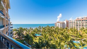 A resort with a view of the ocean, palm trees, and a building with a chimney emitting smoke. - Unlimited Luxury Villas - Playa Royale Condo (Nuevo Nayarit)
