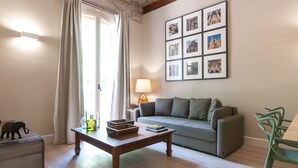 Uma sala de estar com sofá, mesa de centro, luminária e quadros nas paredes.