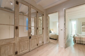 A room with a wooden wardrobe, a bed with a plaid bedspread, and a bedside table with a lamp. - Weflating Suites Sant Antoni Market (Barcelona)