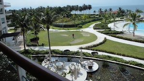 A resort with a pool, palm trees, and a view of the ocean.