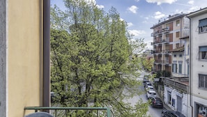 A balcony with a plastic chair, overlooking a street with parked cars and buildings. - ALIANTE TURIST HOUSE (Pisa)