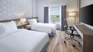 A hotel room with two beds, a desk, a TV, and a view of the outdoors. - Holiday Inn Tabuk by IHG (Tabuk)