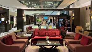 A spacious lobby with a central red sofa, two armchairs, a coffee table, and a reception desk. - Holiday Inn Tabuk by IHG (Tabuk)