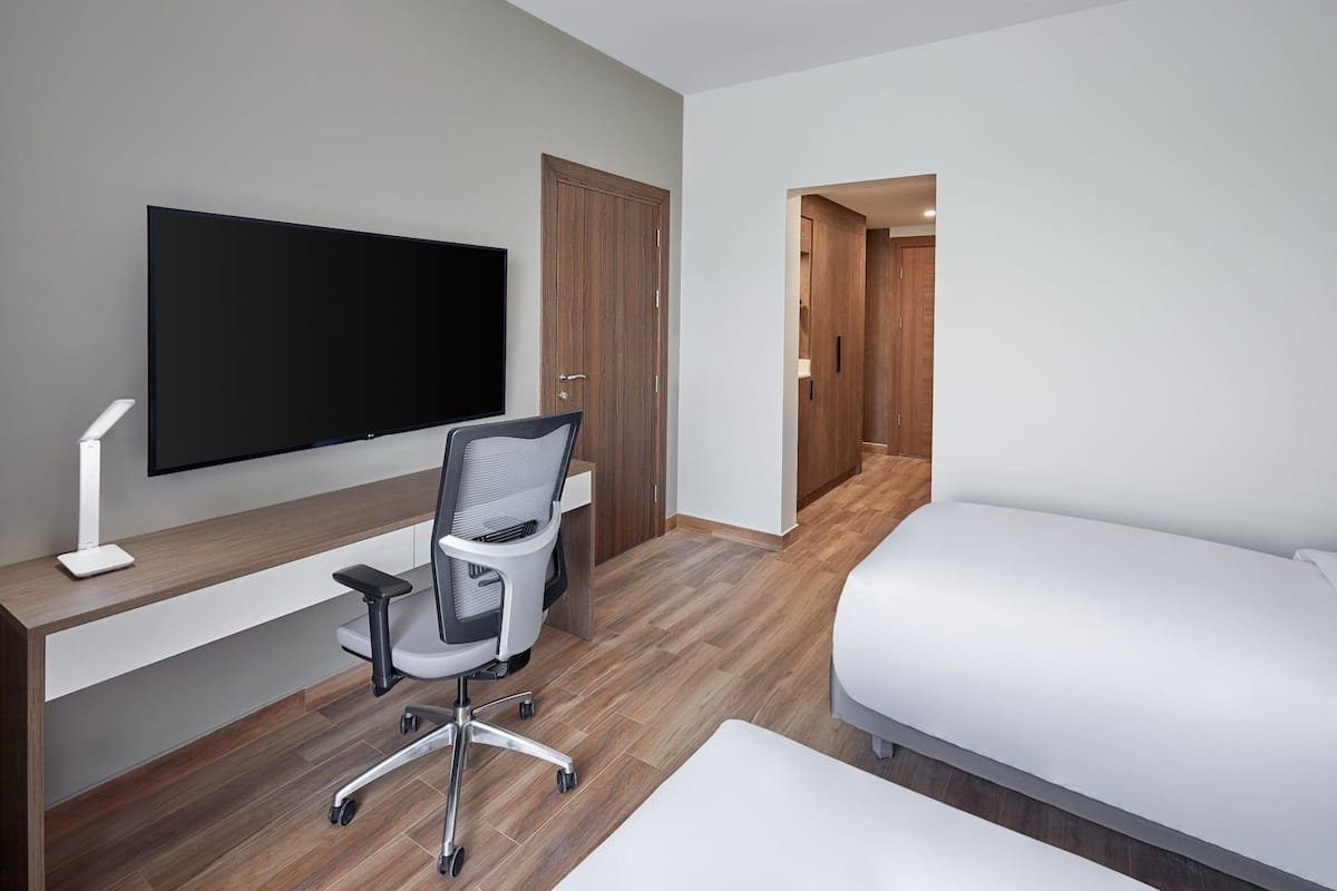 Ett hotellrum med en säng, ett skrivbord med en stol, en tv och en garderob.