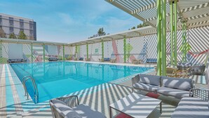 A swimming pool with lounge chairs and umbrellas, surrounded by a modern building. - Holiday Inn Tabuk by IHG (Tabuk)