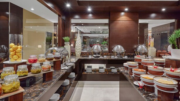 A buffet area with various food items and serving stations, including jars of pickles and covered dishes. - Holiday Inn Tabuk by IHG (Tabuk)