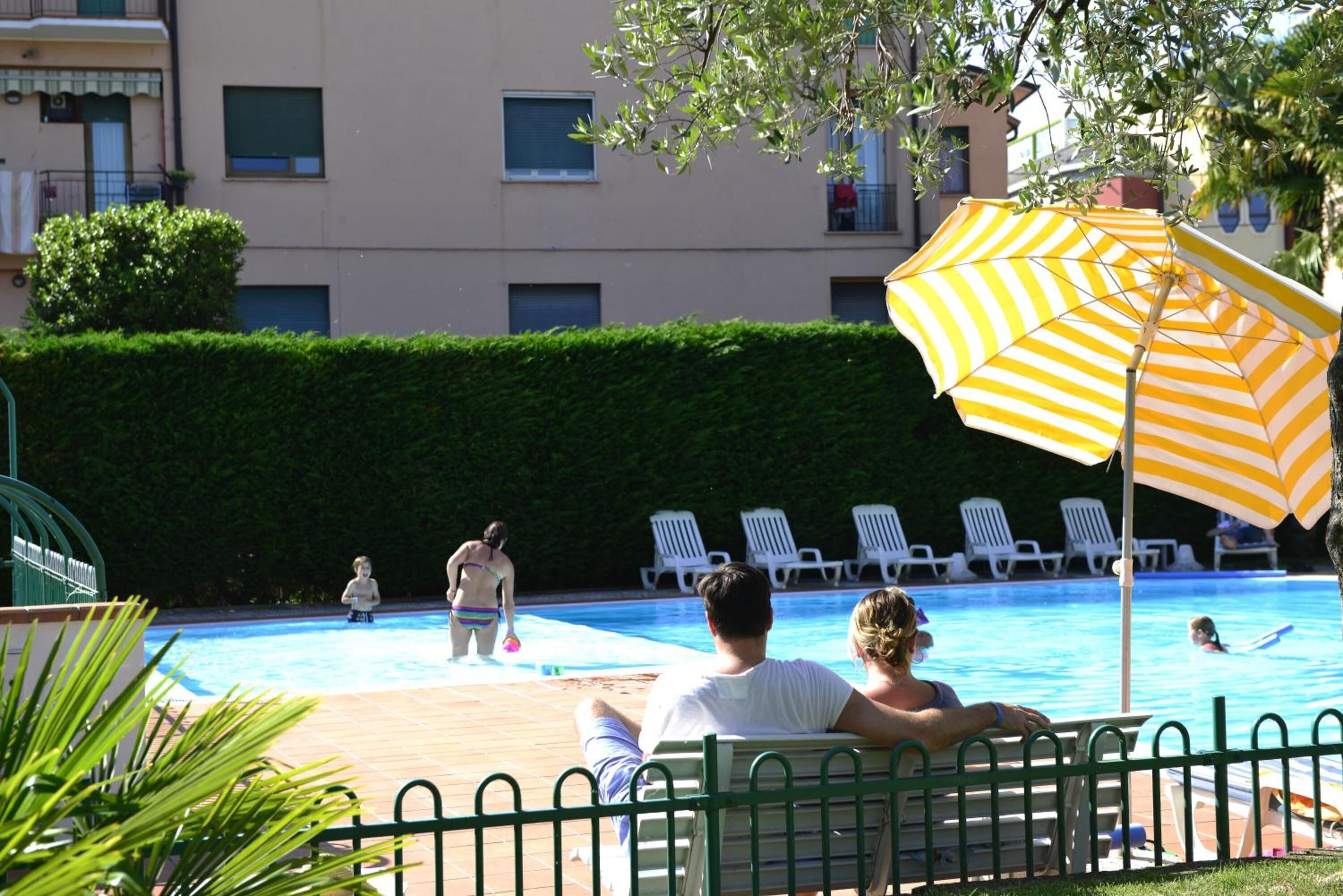 A swimming pool with lounge chairs and an umbrella.