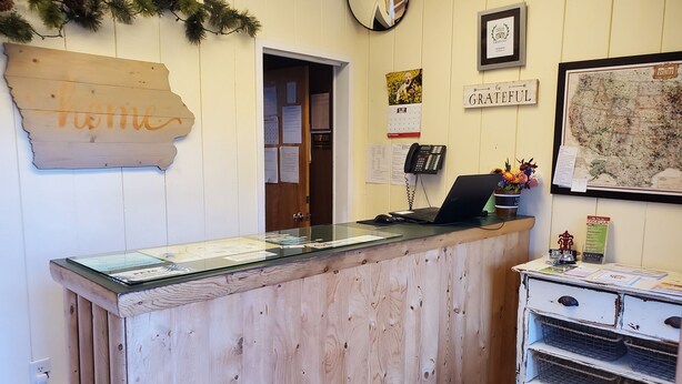 A reception desk with a wooden backdrop, a framed map, and a 'home' sign.