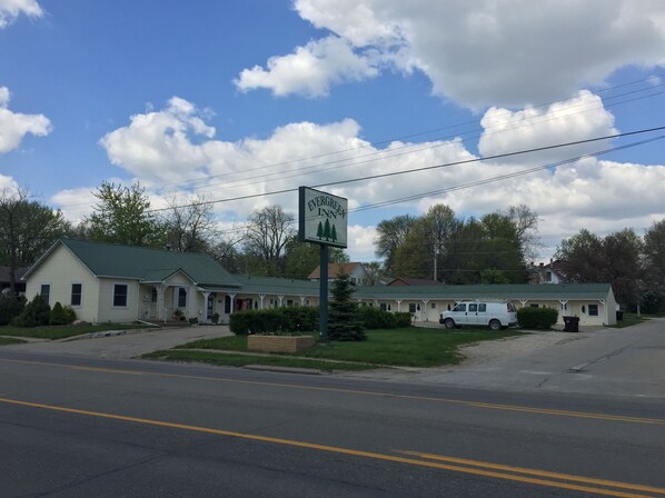 A motel with a green roof, a signboard, and a white van parked in front.