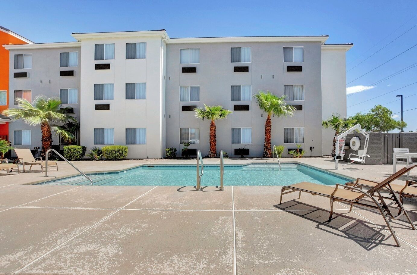 A hotel with a swimming pool, palm trees, and a modern building facade.