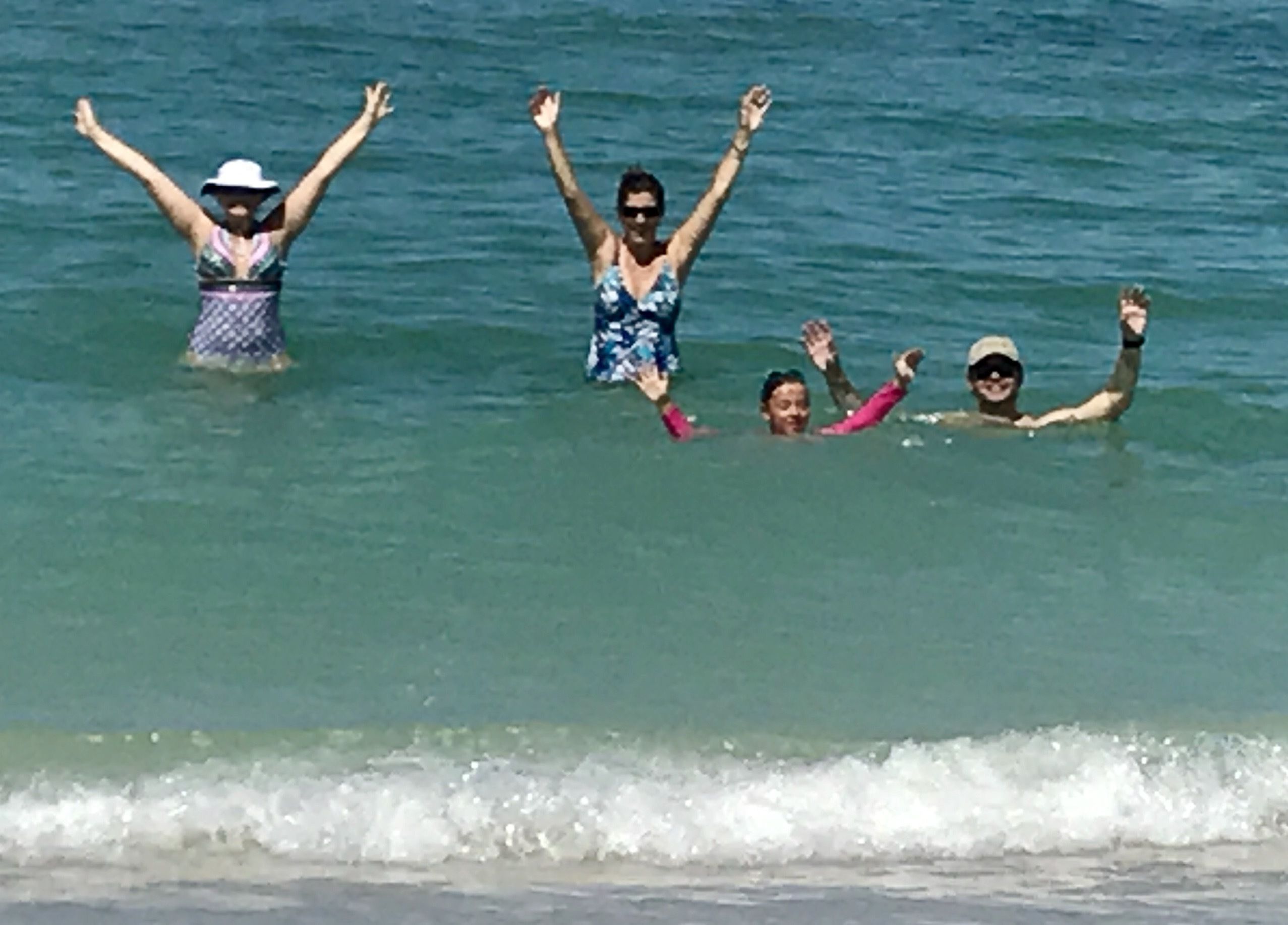 Eine Gruppe von Menschen im Meer, die die Arme in die Luft strecken.