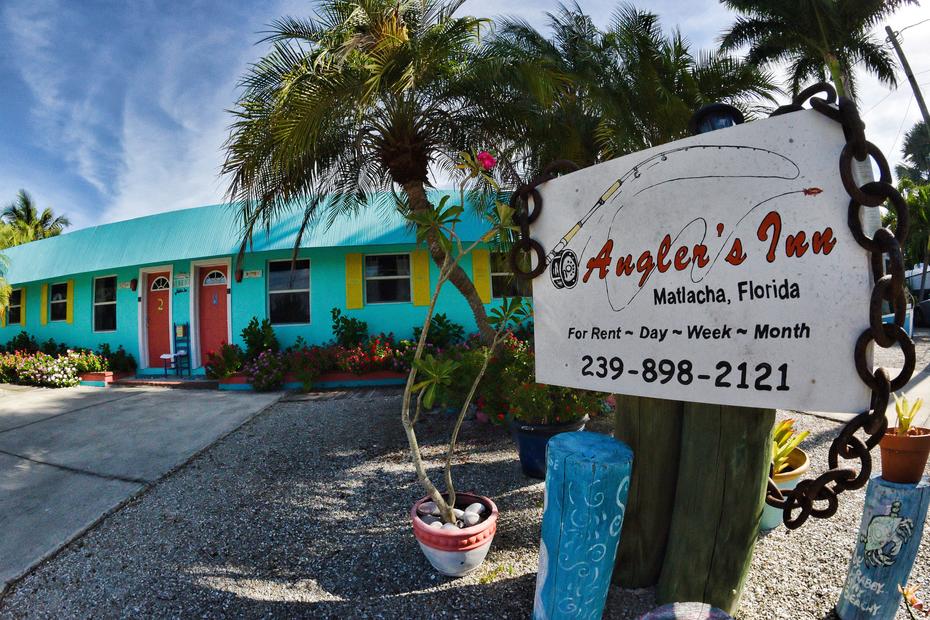 Un edificio colorido con un letrero que anuncia Angler's Inn en Matlacha, Florida, e indica que hay habitaciones disponibles.