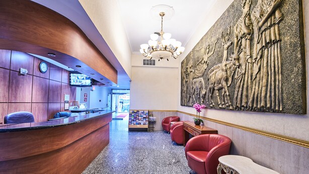A lobby with a reception desk, red chairs, a chandelier, and a large wall mural. - Flushing Hotel (Flushing)