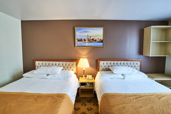 A hotel room with two beds, a nightstand with a lamp, a painting of a cityscape, and a wooden cabinet. - Flushing Hotel (Flushing)