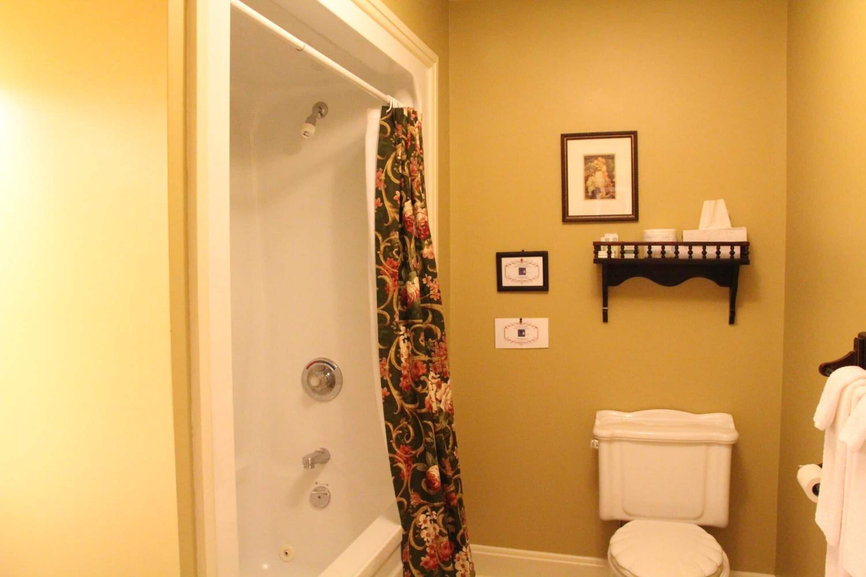 A bathroom with a shower, toilet, and a towel rack with towels.