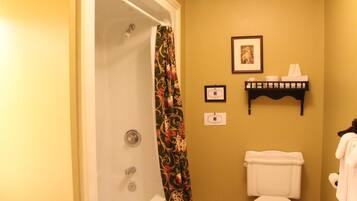 A bathroom with a shower, toilet, and a towel rack with towels.