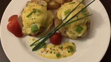 Ein Teller mit Eggs Benedict, Rösti, Erdbeeren und Schnittlauch.